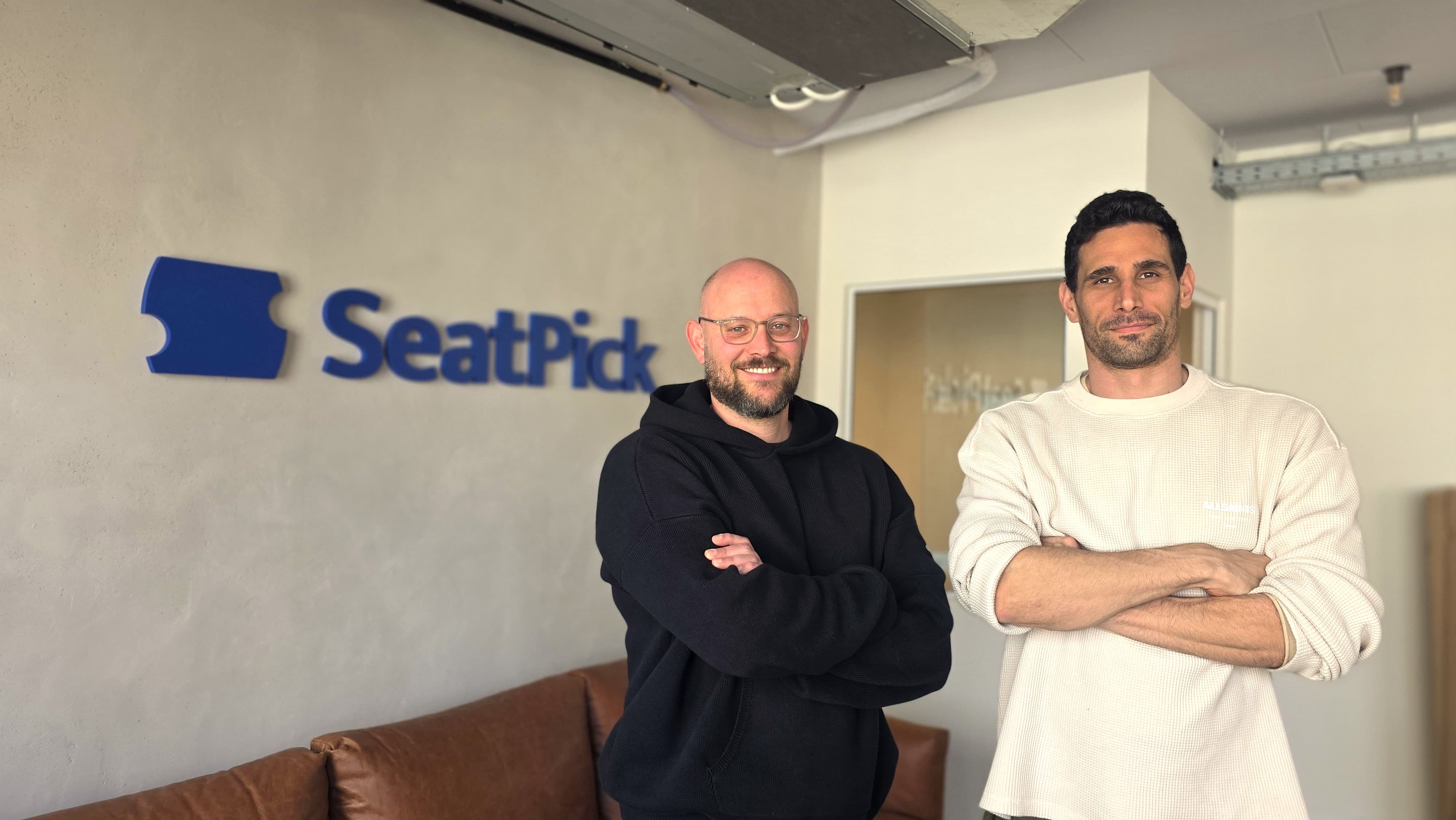 Guy Kogel and Gilad Zilberman, co-founders of SeatPick, standing in front of the company logo